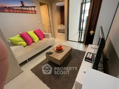 Modern living room with cozy sofa, vibrant cushions, and sleek TV setup in stylish apartment.