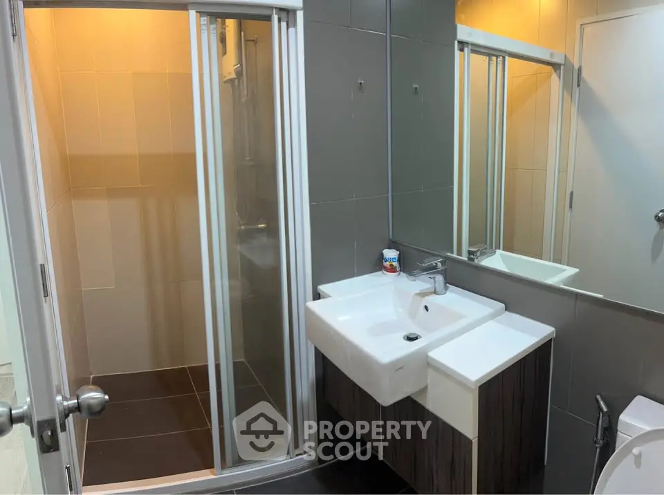 Modern bathroom with sleek shower and stylish sink in contemporary apartment.