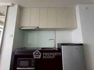 Modern kitchen with sleek cabinets, built-in microwave, and compact fridge in a stylish apartment.