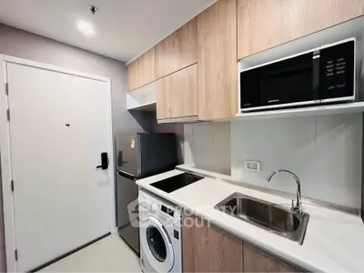 Modern compact kitchen with built-in appliances and sleek cabinetry in a stylish apartment.