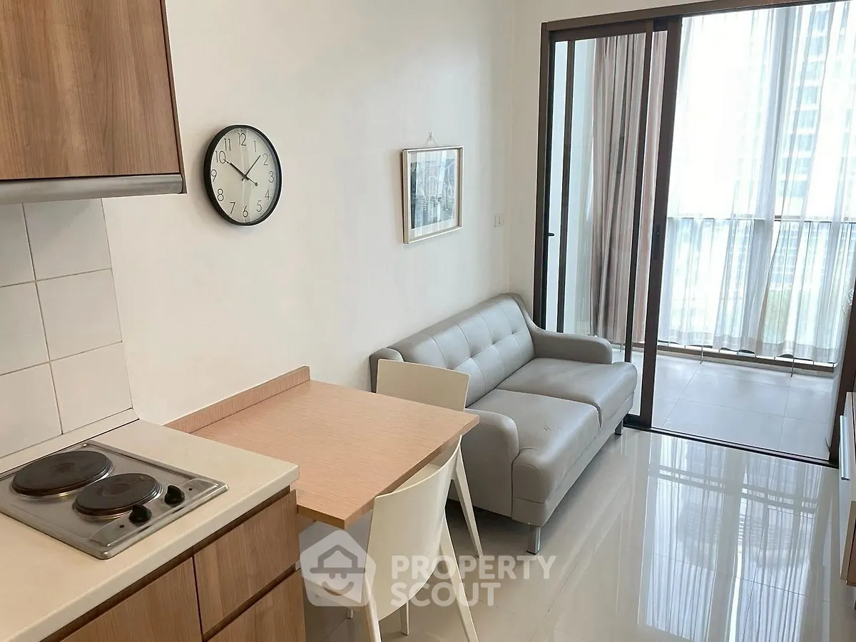 Modern apartment with sleek kitchen and cozy living area, featuring large windows for natural light.