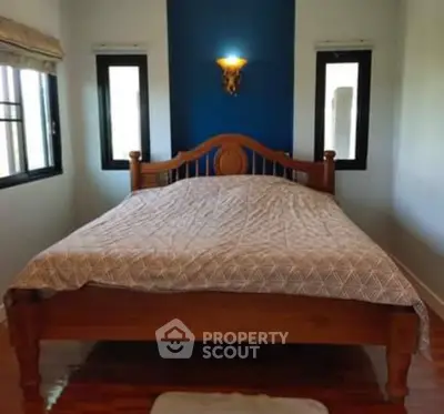 Cozy bedroom with wooden bed frame and elegant lighting, perfect for relaxation.