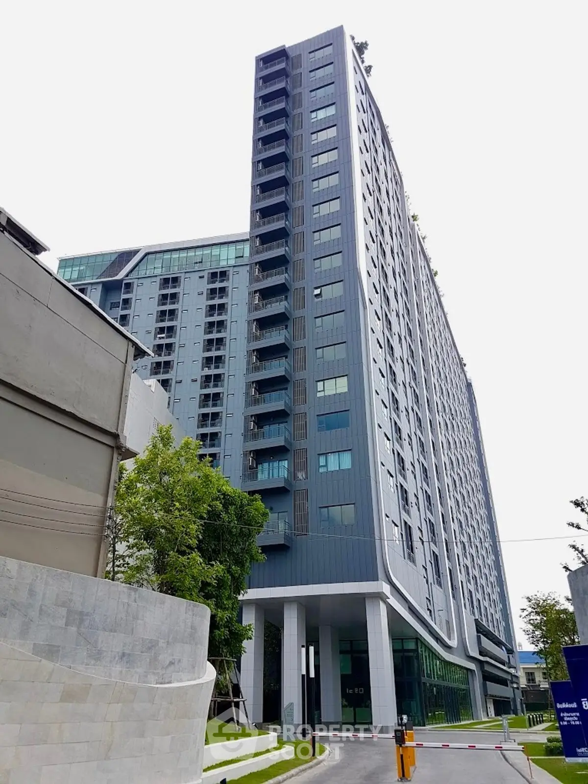 Modern high-rise residential building with sleek design and lush greenery.