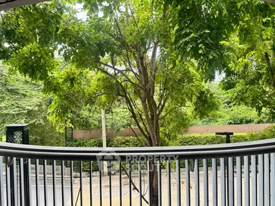 Charming balcony view with lush greenery and street scenery, perfect for relaxation and enjoying nature.