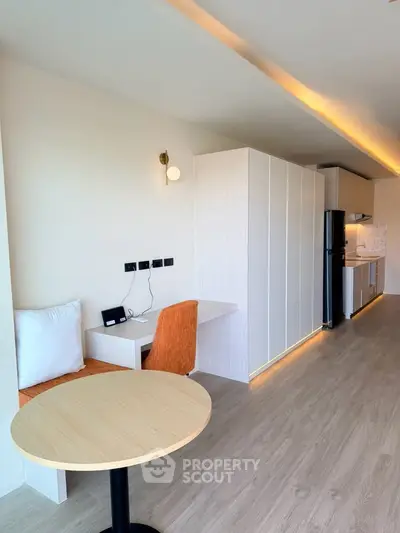 Modern open-plan living area with sleek kitchen and cozy dining space, featuring contemporary lighting and wood flooring.
