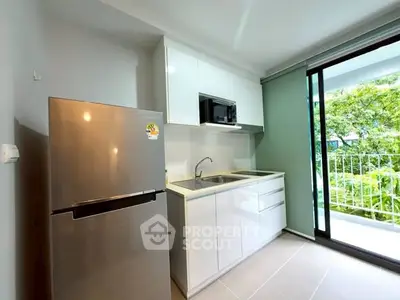 Modern kitchen with sleek cabinetry and balcony view in a stylish apartment.