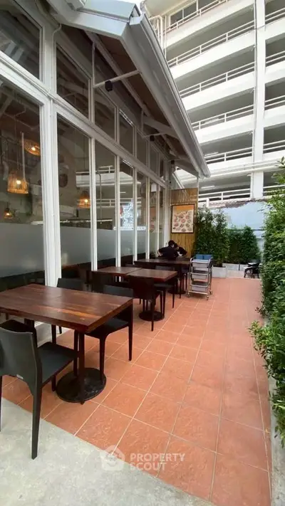 Charming outdoor seating area with modern furniture and lush greenery, perfect for relaxation and dining.