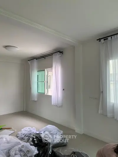 Bright and airy room with large windows and white curtains, perfect for natural light.