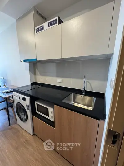 Modern compact kitchen with washing machine and microwave in sleek apartment