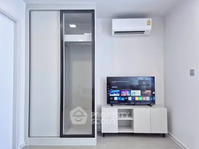 Modern living room with sleek TV setup and air conditioning in a stylish apartment.