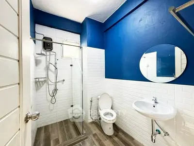 Modern bathroom with blue accents, glass shower, and sleek fixtures.
