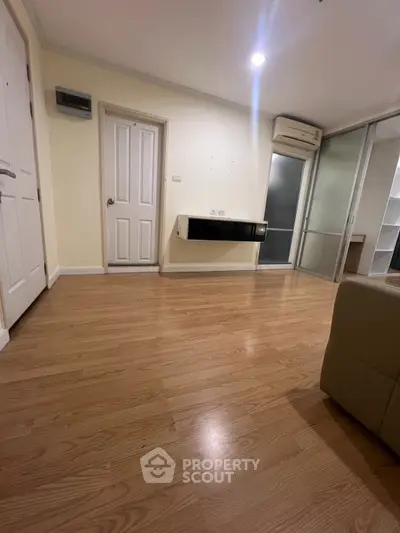 Spacious living room with wooden flooring and modern air conditioning unit.