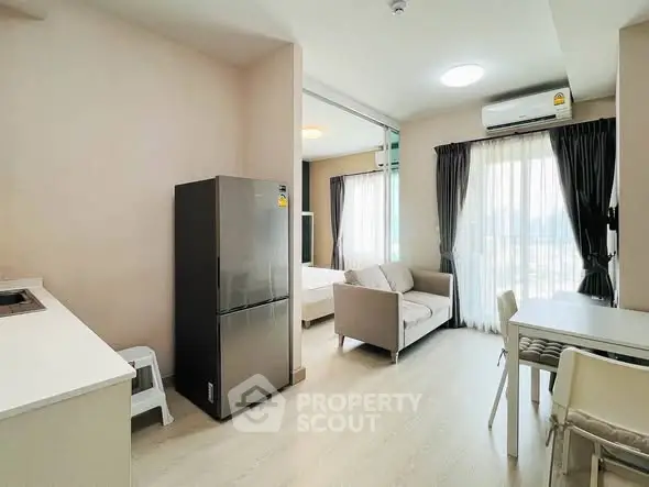 Modern apartment interior with open layout, featuring a cozy living area, dining space, and kitchen with stainless steel fridge.