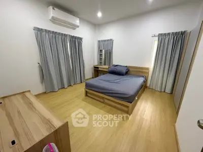 Spacious bedroom with modern wooden flooring and stylish curtains