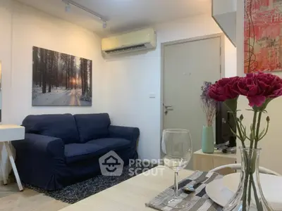 Cozy living room with blue sofa, wall art, and dining setup in modern apartment.