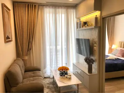 Modern living room with cozy sofa, TV, and elegant decor leading to a stylish bedroom.