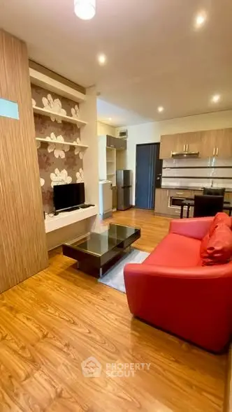 Modern living room with red sofa, TV, and wooden flooring in stylish apartment.