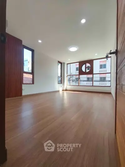 Spacious and bright living room with large windows and wooden flooring, perfect for modern living.
