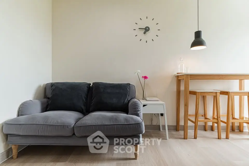 Modern living room with cozy gray sofa and stylish bar stools under pendant light.