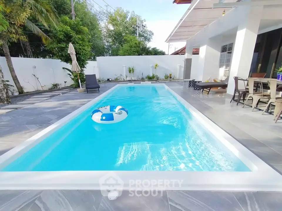 Luxurious modern home with pristine swimming pool and elegant outdoor seating area.