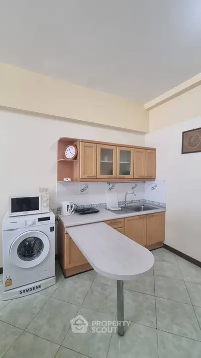 Compact kitchen with washing machine and breakfast bar in cozy apartment.