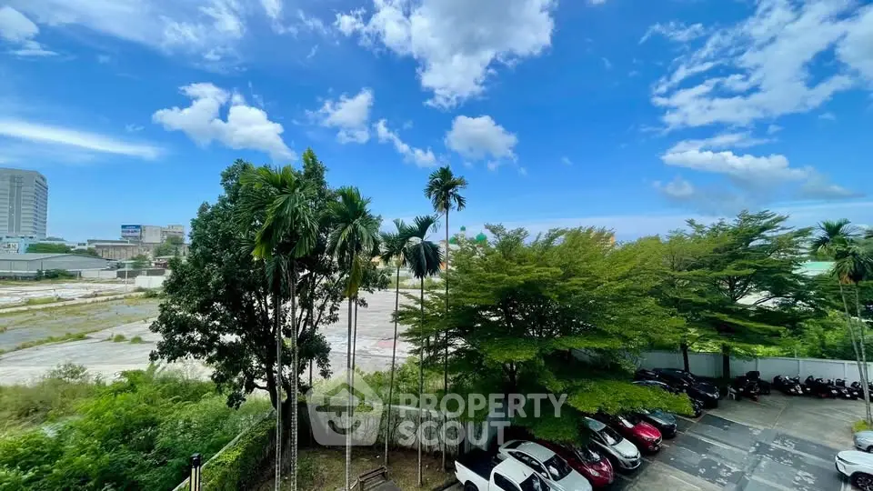 Scenic view of lush greenery and parking area under a vibrant blue sky.