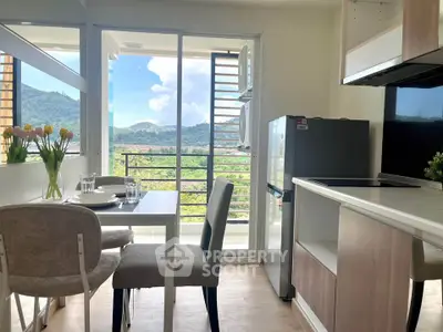 Modern kitchen with dining area and scenic mountain view from balcony.