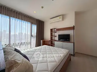 Spacious bedroom with large windows and modern furnishings in a high-rise apartment.