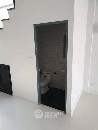 Compact bathroom under staircase with modern design and white tiles