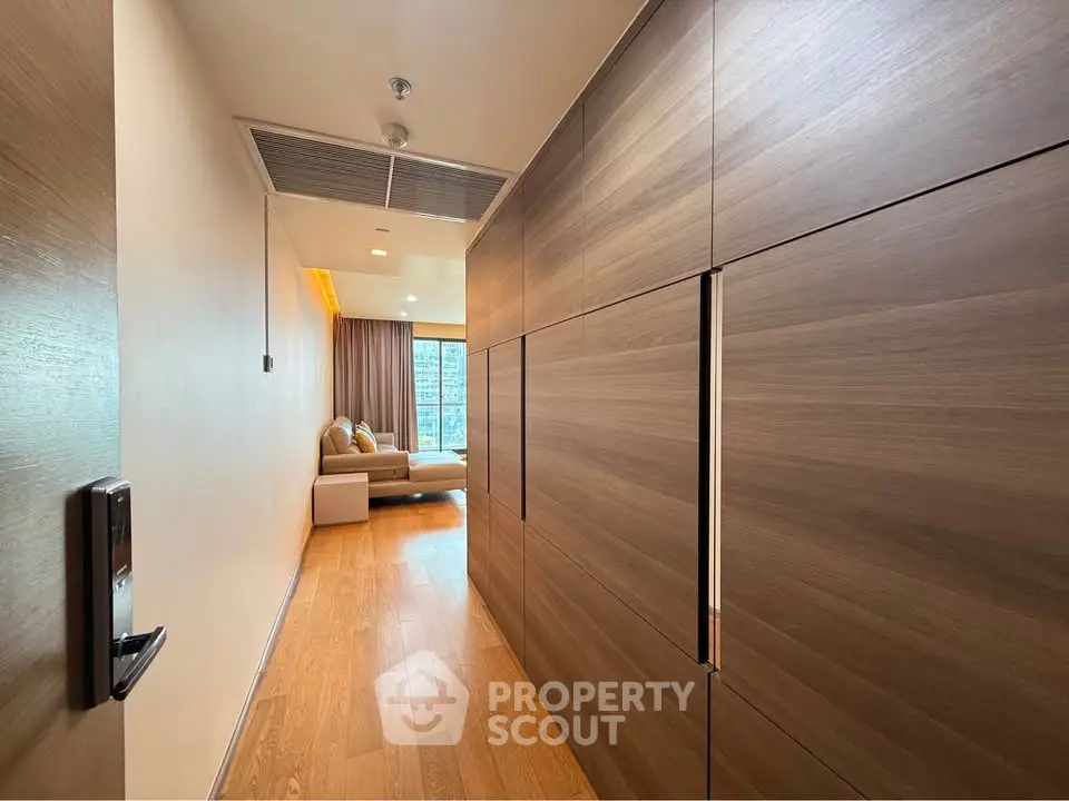 Modern apartment hallway leading to a cozy living room with wooden flooring and stylish decor.