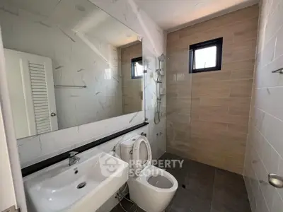 Modern bathroom with sleek fixtures and large mirror in contemporary home.
