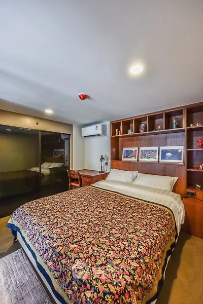 Cozy bedroom with built-in wooden shelves and air conditioning, perfect for relaxation.