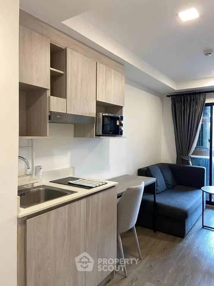 Modern studio apartment with compact kitchen and cozy living area, featuring sleek cabinetry and natural light.