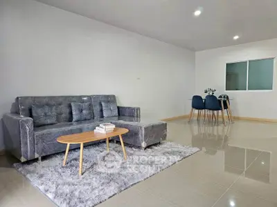 Spacious modern living room with plush gray sofa and elegant dining area.