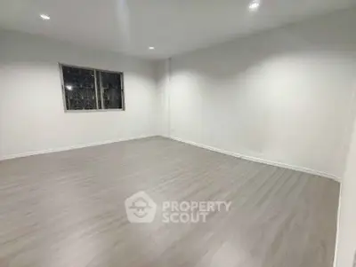 Spacious empty room with wooden flooring and bright lighting, perfect for customization.