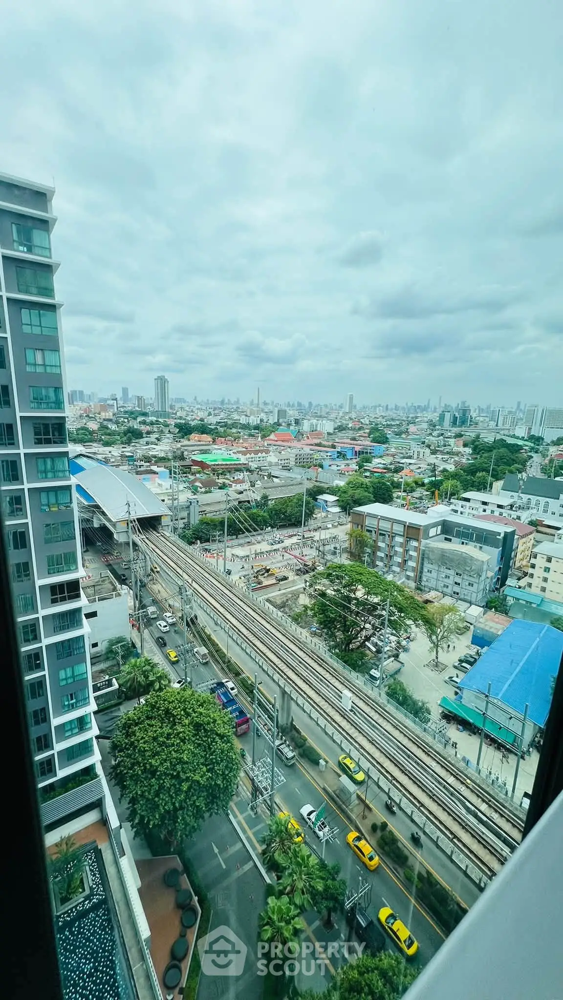Stunning cityscape view from high-rise building with urban skyline and railway tracks.