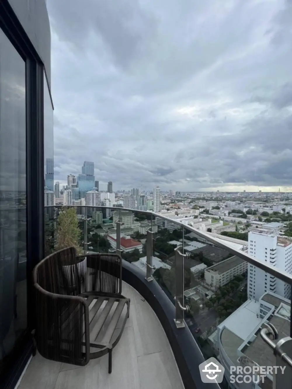 Stunning city view from modern high-rise balcony with sleek glass railing.