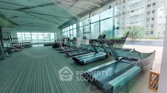 Modern gym with treadmills and large windows in a residential building