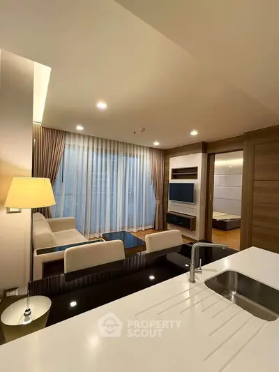 Modern living room with open kitchen, elegant decor, and ample natural light