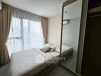 Modern bedroom with large window and mirrored wardrobe in stylish apartment.