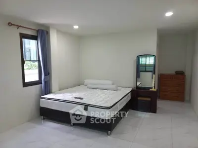 Spacious bedroom with modern decor and natural light, featuring a comfortable bed and stylish furniture.