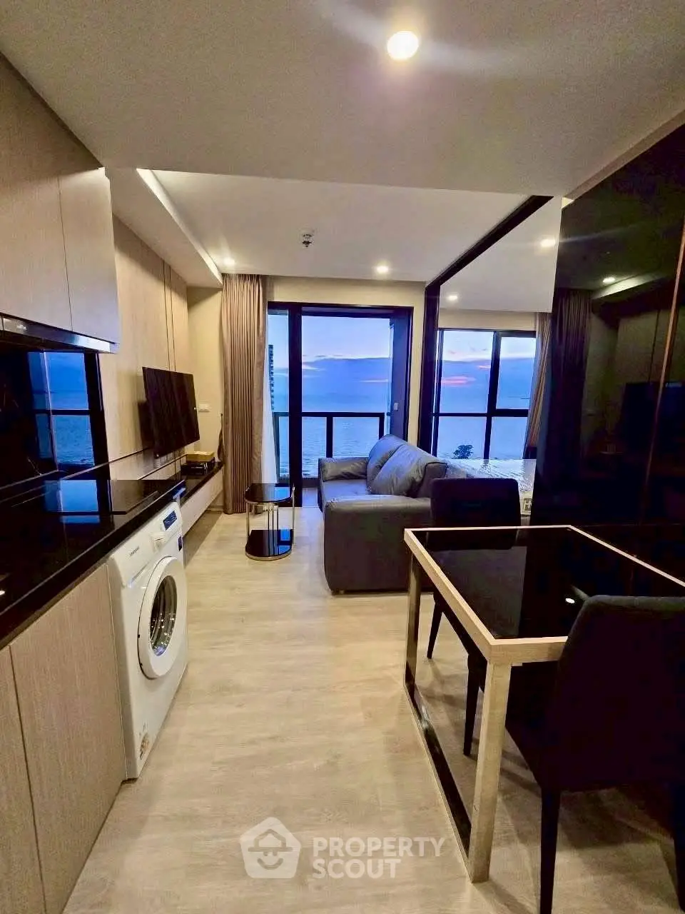 Modern living room with ocean view, featuring sleek furniture and built-in appliances.