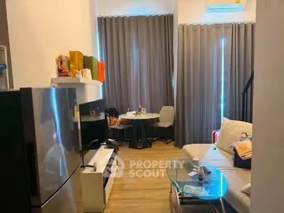 Modern living room with stylish decor and cozy seating area, featuring a sleek refrigerator and elegant curtains.