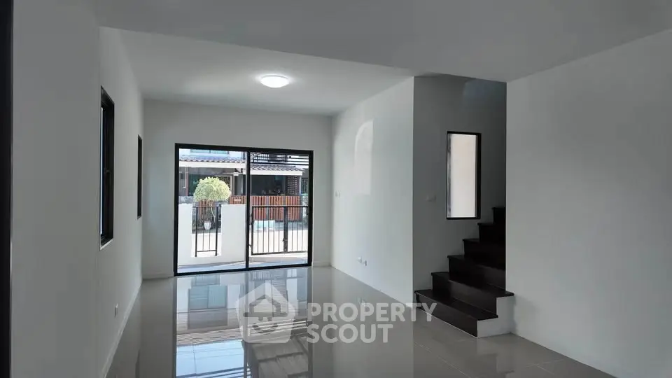 Modern living room with sleek staircase and large windows for natural light.