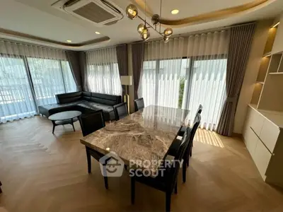 Luxurious living room with elegant marble dining table and modern black sofa, featuring large windows and stylish lighting.