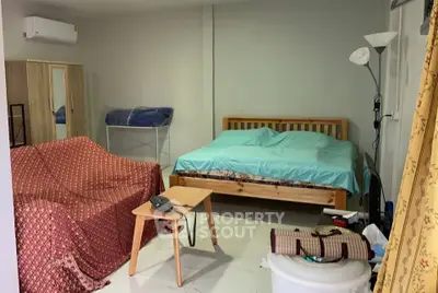 Cozy bedroom with wooden bed, air conditioning, and compact seating area.