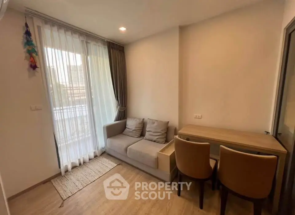Cozy living room with natural light, modern sofa, and dining area in a stylish apartment.