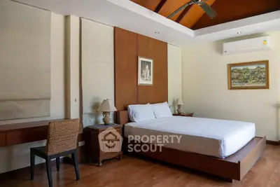 Spacious bedroom with wooden flooring and modern decor, featuring a comfortable bed and elegant furnishings.