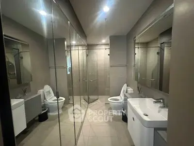 Modern bathroom with sleek design, featuring glass shower and dual sinks.