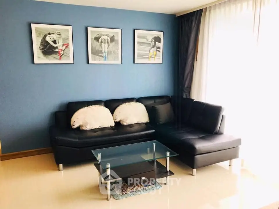 Stylish living room with modern black sofa and glass coffee table, enhanced by elegant wall art and natural light.